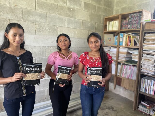 Three young female students holding bags of MannaPack soy